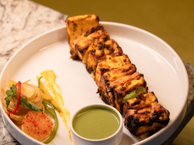 Chargrilled cubes on a white plate with green chutney and a small salad.