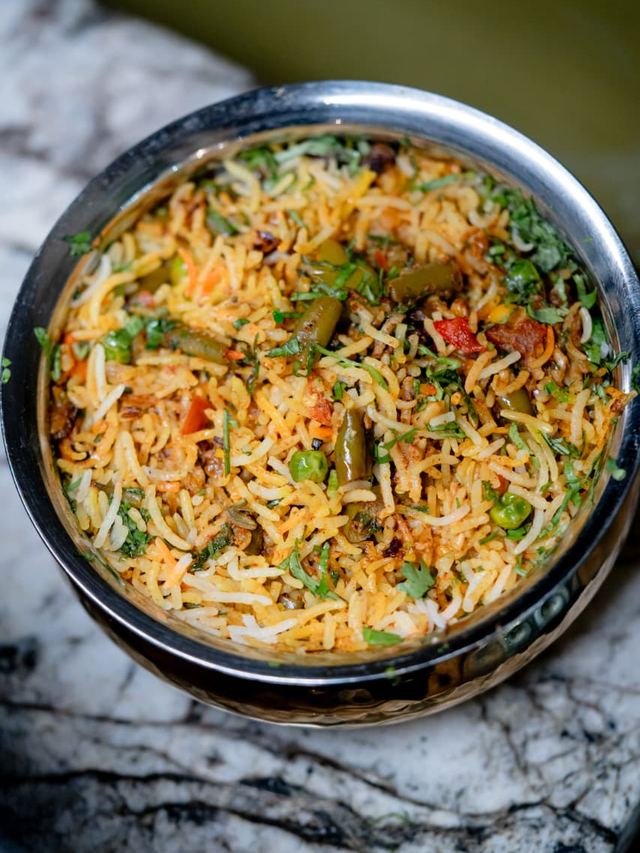 Vegetable rice with herbs and green peas in a steel handi.